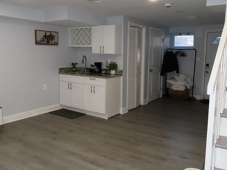 Basement with a wet bar an outdoor exit, laundry, full bathroom, and additional storage space.