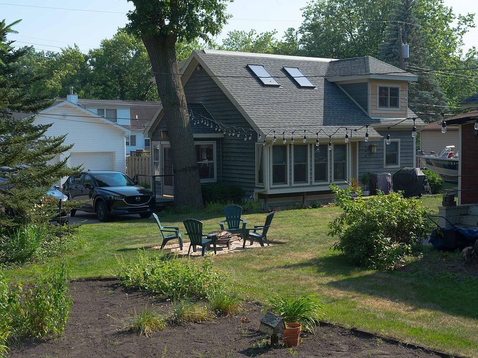 Exterior, looking thru garden and fire pit area surrounded by lawn and trees.