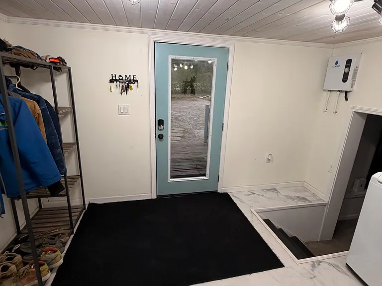 Functional entry/mudroom with durable tile flooring, overhead lighting, and space for coats and everyday gear.