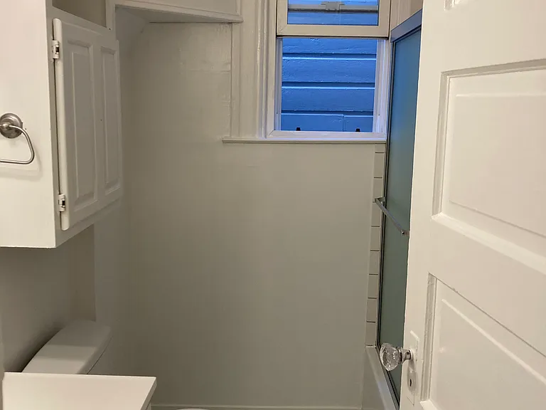 Bathroom with full shower and storage behind bathroom door