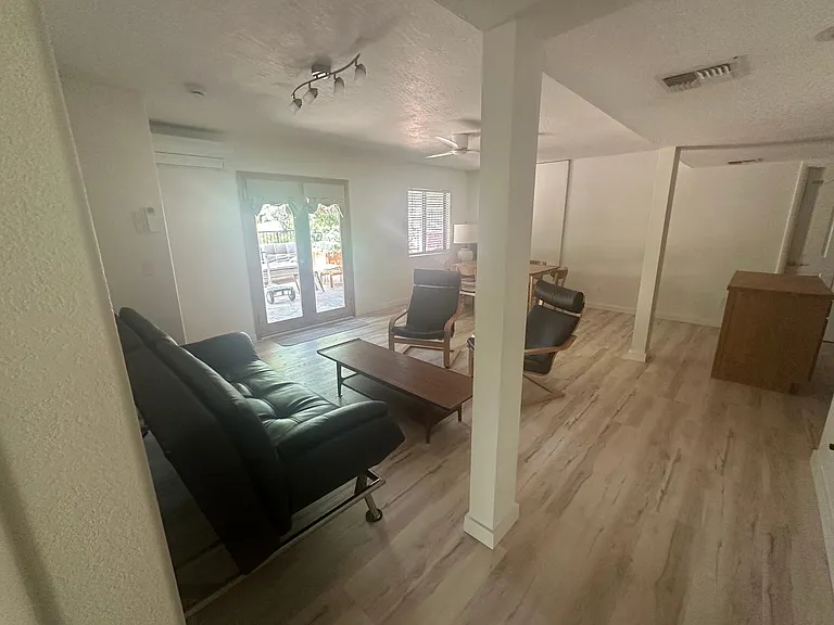 Living room with table and 6 chairs, coffee table, 2 ikea poang chairs and leather coach. Kitchen island. New ceiling fan and paint and new luxury vinyl flooring throughout unit.