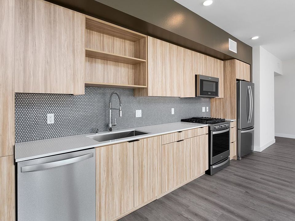 Open concert kitchen with quartz countertops backsplash, stainless steel appliances and hard surface flooring