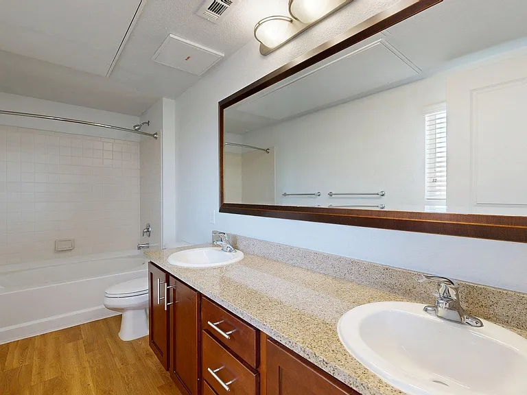 Apartment bathroom with wood-style flooring.