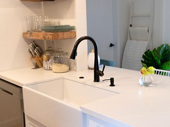 Kitchen with floating shelves (dishes included) granite countertops, touches sink and garbage disposal.