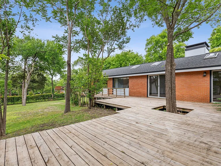 Expansive outdoor deck crafted with wood planks, integrating mature trees within its design