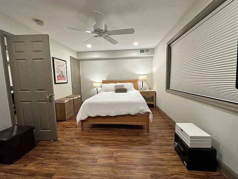 Huge bedroom, with a beautiful large window for natural light during the day, plus custom blackout curtains and a quiet ceiling fan for a great night sleep. This image shows one of three custom-finished closets within the bedroom.