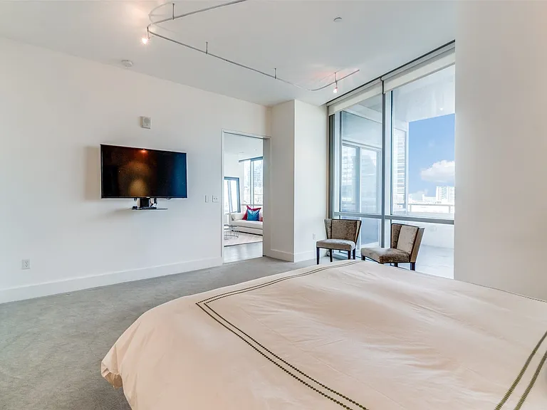 Bedroom with carpet flooring, rail lighting, and floor to ceiling windows