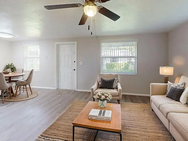 Bright and airy living room with modern decor, featuring a cozy sofa, sleek coffee table, and elegant dining area, perfect for relaxation and entertaining.