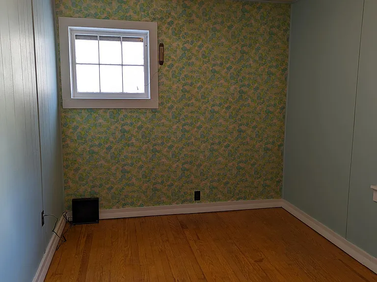 Smaller bedroom features two windows, vintage wallpaper and a good sized closet