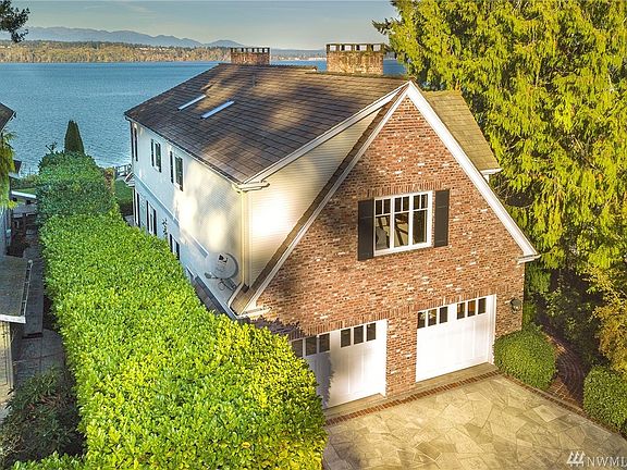 This "lane side" view of the non waterside of the home highlights the historic used brick surrounding the garage and on the beautiful chimneys.  The garage has custom garage doors, includes finished storage and enjoys sealed concrete floors.  The siding is New England style small slat cedar.  The roof was completely replaced in the fall of 2016 with an old growth cedar shingle roof which has water tight sub roof under the shingles and is guaranteed for 50 years.  The gutters were also replaced i