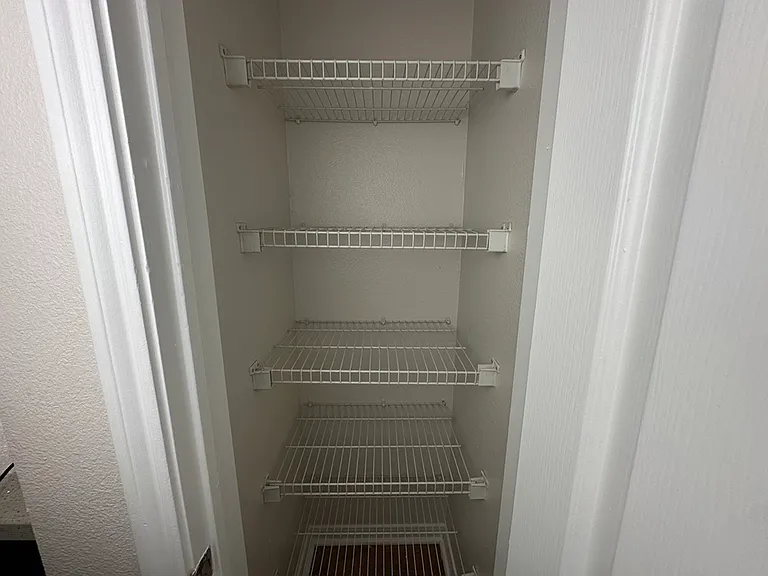 Spacious pantry with four wire shelves, perfect for organizing and maximizing storage space. Spacious pantry with four wire shelves, perfect for organizing and maximizing storage space.
