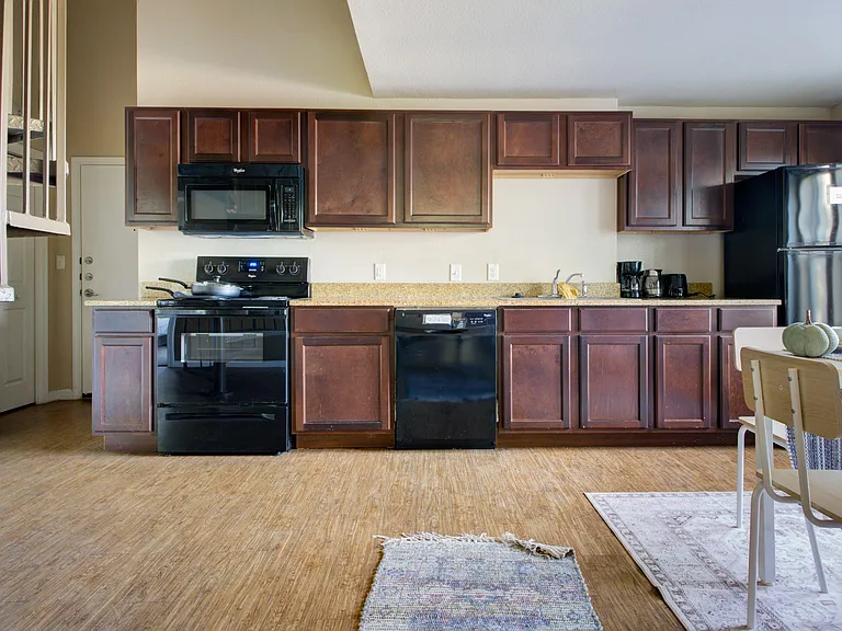 Spacious kitchen with ample dark-wood cabinetry, long counters, and black appliances including range, microwave, dishwasher,