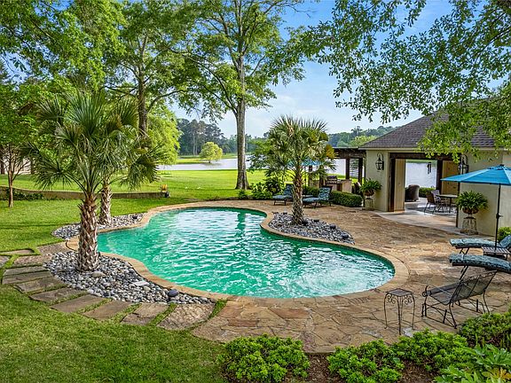 Freeform swimming pool with integrated planter, natural stone patio, and palm tree landscaping