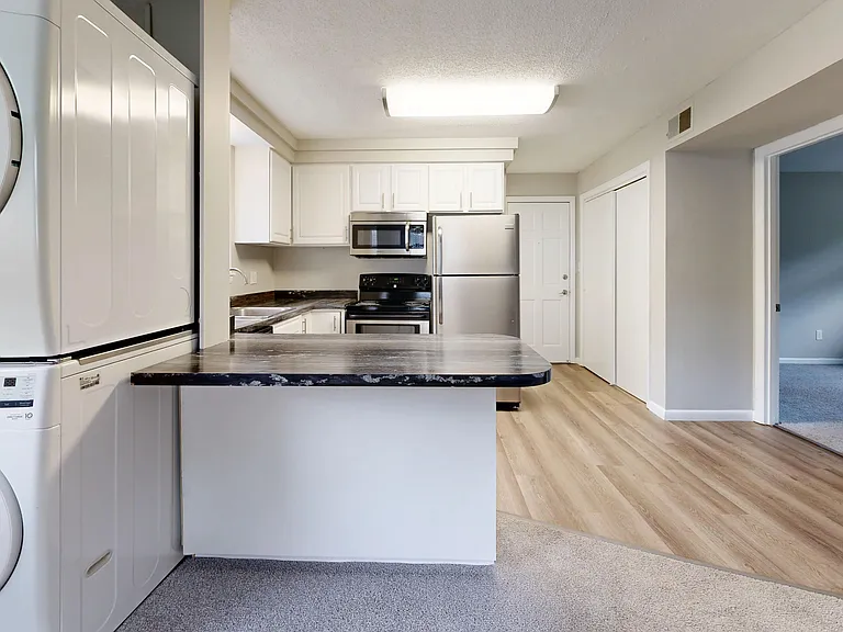 The Valley floor plan offers a kitchen with modern appliances, including a washer and dryer, stainless steel refrigerator, oven, and microwave, complemented by stylish countertops and cabinetry.