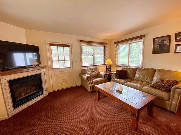 Living Room with gas fire place and door to balcony overlooking the Fall River.
