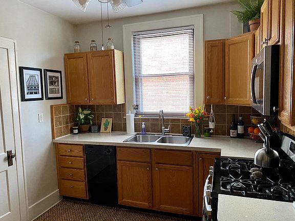 Kitchen features modern gas range, microwave, dishwasher and fridge.