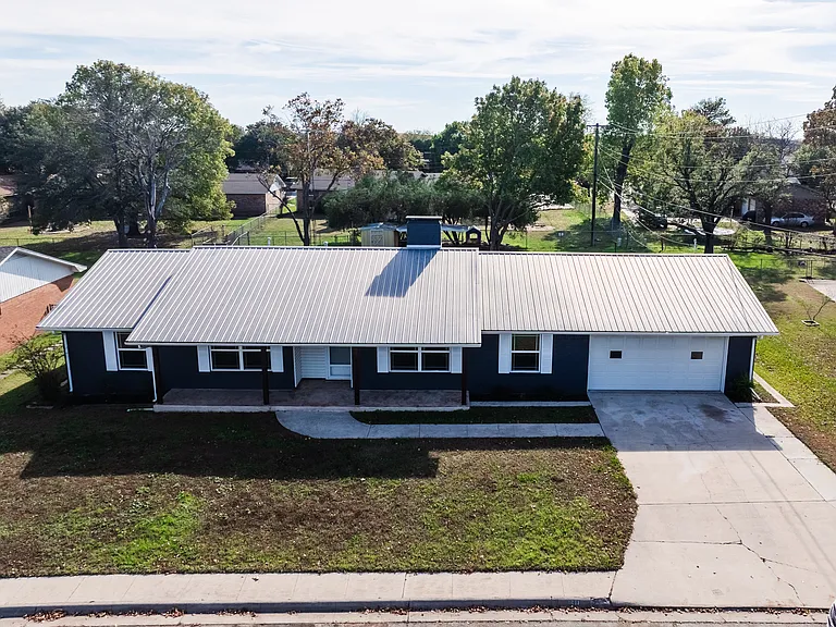 Rear view of the home with expansive backyard and green space