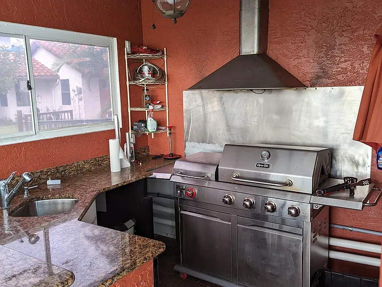 This outdoor gas grill and kitchenette is equipped with lighting, a ceiling fan, sink, small fridge and all the tools you need to produce an amazing meal to enjoy poolside.