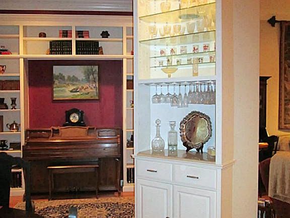 A built-in dry bar with Carrera marble top, glass shelves with lighting, drawers and cabinet storage