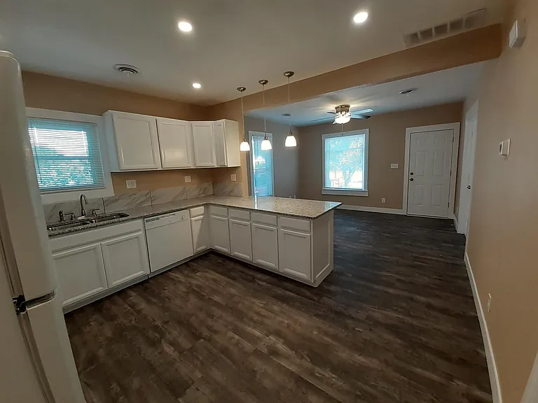 Kitchen with granite countertops, tile backsplash, plentiful cabinet space, dishwasher, and new appliances.
