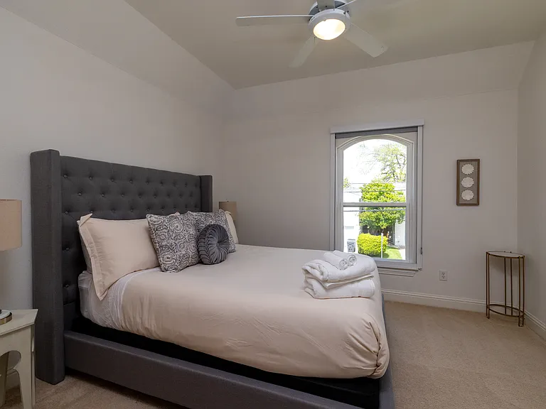 Cozy queen bedroom with private ensuite bathroom access.
Sunlit bedroom with comfortable queen bed and view.
