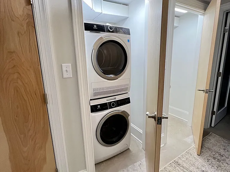 Full-size stacking washer dryers on bedroom level (storage closet open to right).