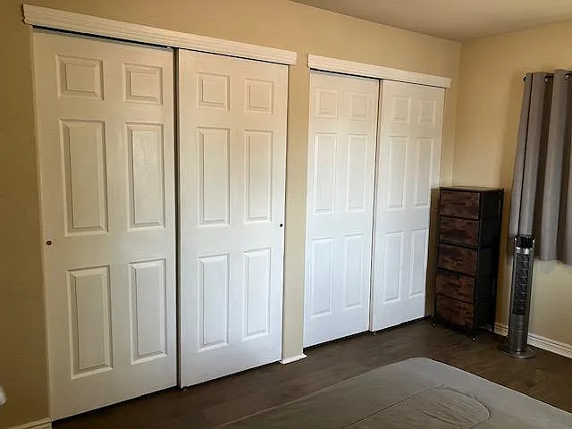 Bedroom with two large sliding-door closets, durable flooring, and space for a dresser with window-side light.