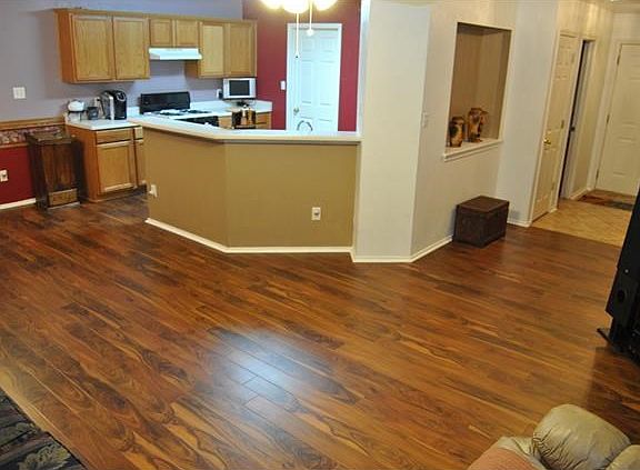 A view of the living room and kitchen.  New flooring and paint.