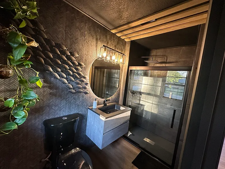 Primary suite features wood, stone and herringbone tiles. The illuminated mirror and floating vanity (with underlighting) continue the modern theme.
