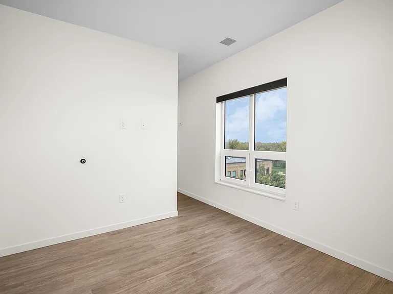 Bright and airy room with large window offering scenic views, featuring sleek hardwood floors and minimalist white walls. Bright and airy room with large window offering scenic views, featuring sleek hardwood floors and minimalist white walls.