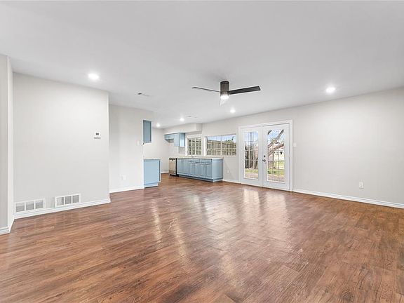 Unfurnished living room with ceiling fan, dark hardwood / wood-style flooring, and french doors