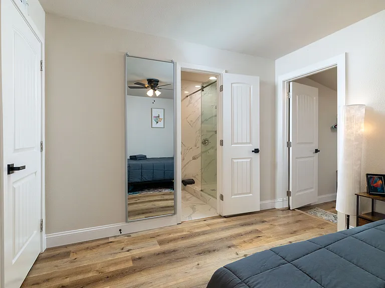 Spacious primary bedroom with a comfy queen bed, walk-in closet with extra storage, attached bathroom, and a dedicated workspace/vanity. Peaceful, bright, and perfect for relaxing or getting work done.