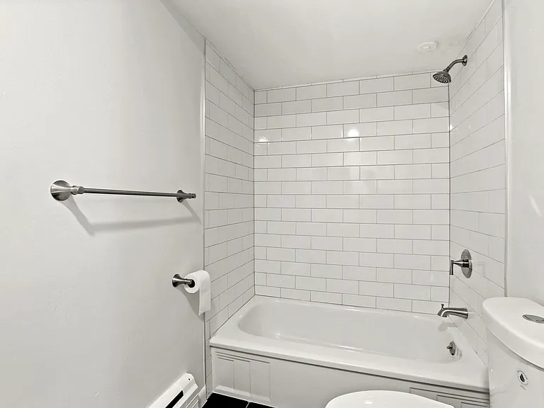 Bright and modern bathroom featuring sleek white subway tiles and a spacious bathtub, offering a clean and refreshing ambiance.