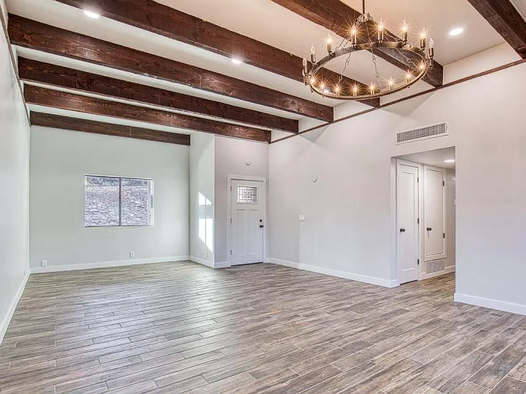 great room has high open beam ceiling with tile flooring that looks like wood