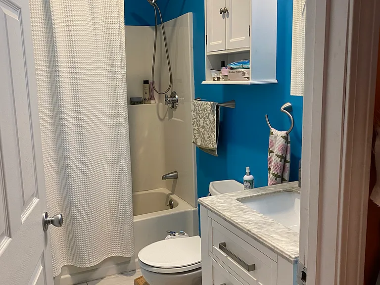 Bath has tub/shower, ceramic tile, storage cabinets, fan, window.