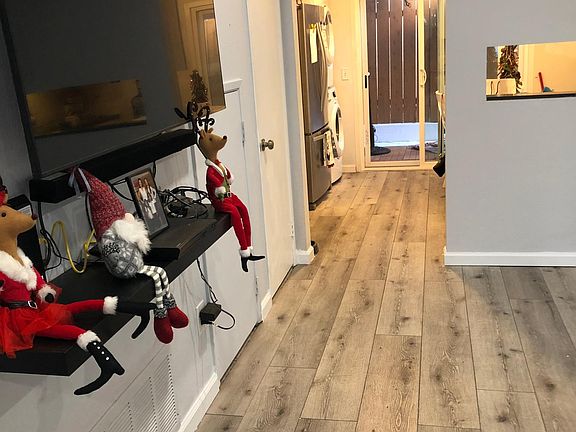 Living room in front of stairs looking into kitchen. Window opening from stove area.