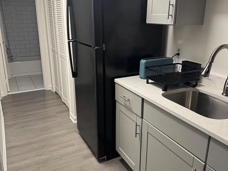 Efficient kitchen with ample shaker cabinetry, quartz-look counters, stainless sink, and a full-size refrigerator for easy me