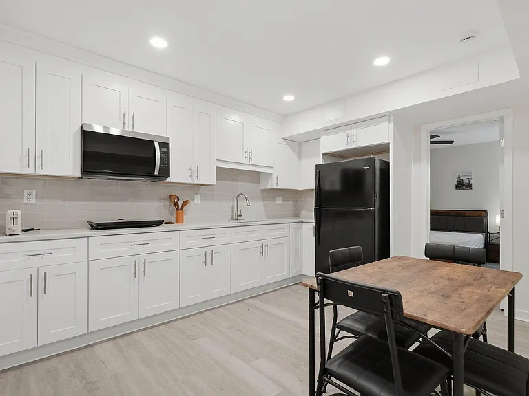 Spacious kitchen with ample white cabinetry, full-size refrigerator, microwave, and a dedicated dining table for meals.