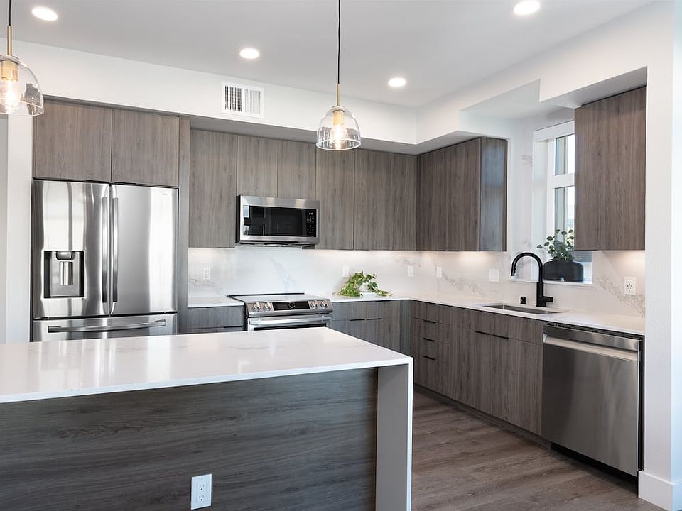 Signature Collection Kitchen with wood cabinetry, marbled quartz countertop and backsplash, upgraded stainless steel appliances, and hard surface flooring