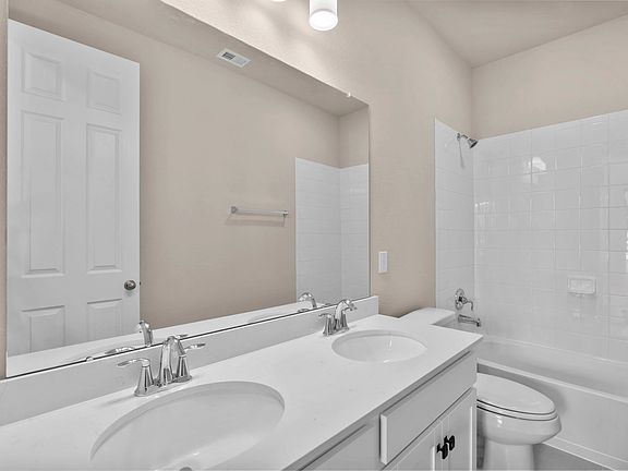 Stylish secondary bath with a shower tub combo and dual-sink vanity featuring gray cabinets and ligh