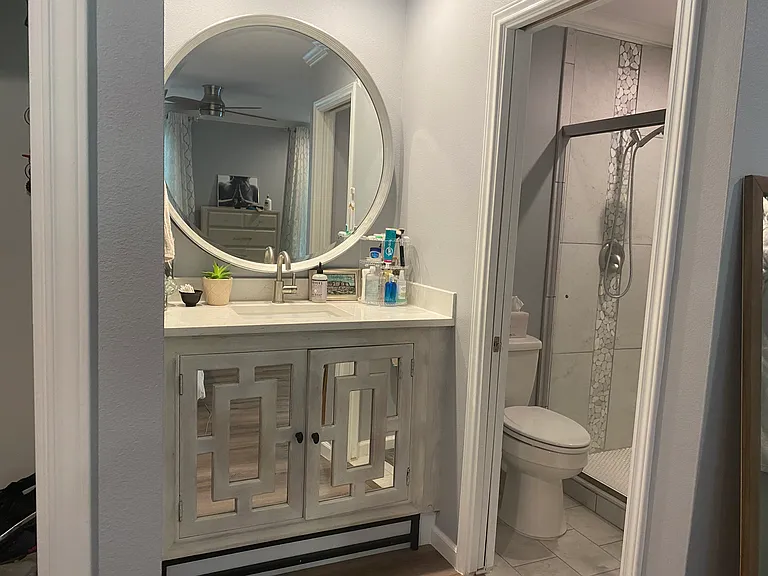 En suite primary bathroom with high countertops and walk-in shower with detachable showerhead.