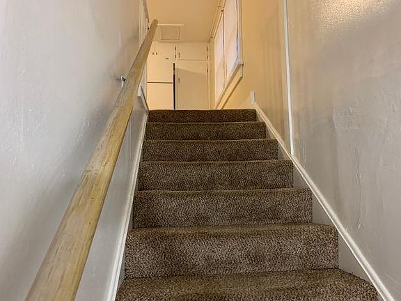 Stairs from front door up to apartment; broom closet next to fridge has attic storage behind it