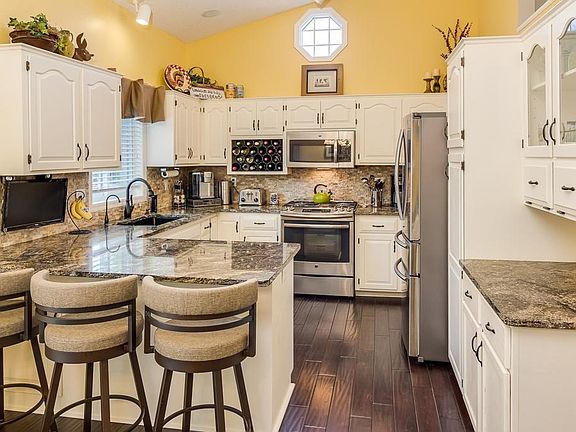 Updated kitchen with painted white cabinets, granite, stone backsplash, stainless appliances.