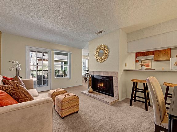 A living room with fireplace, glass door out to the patio, and breakfast bar