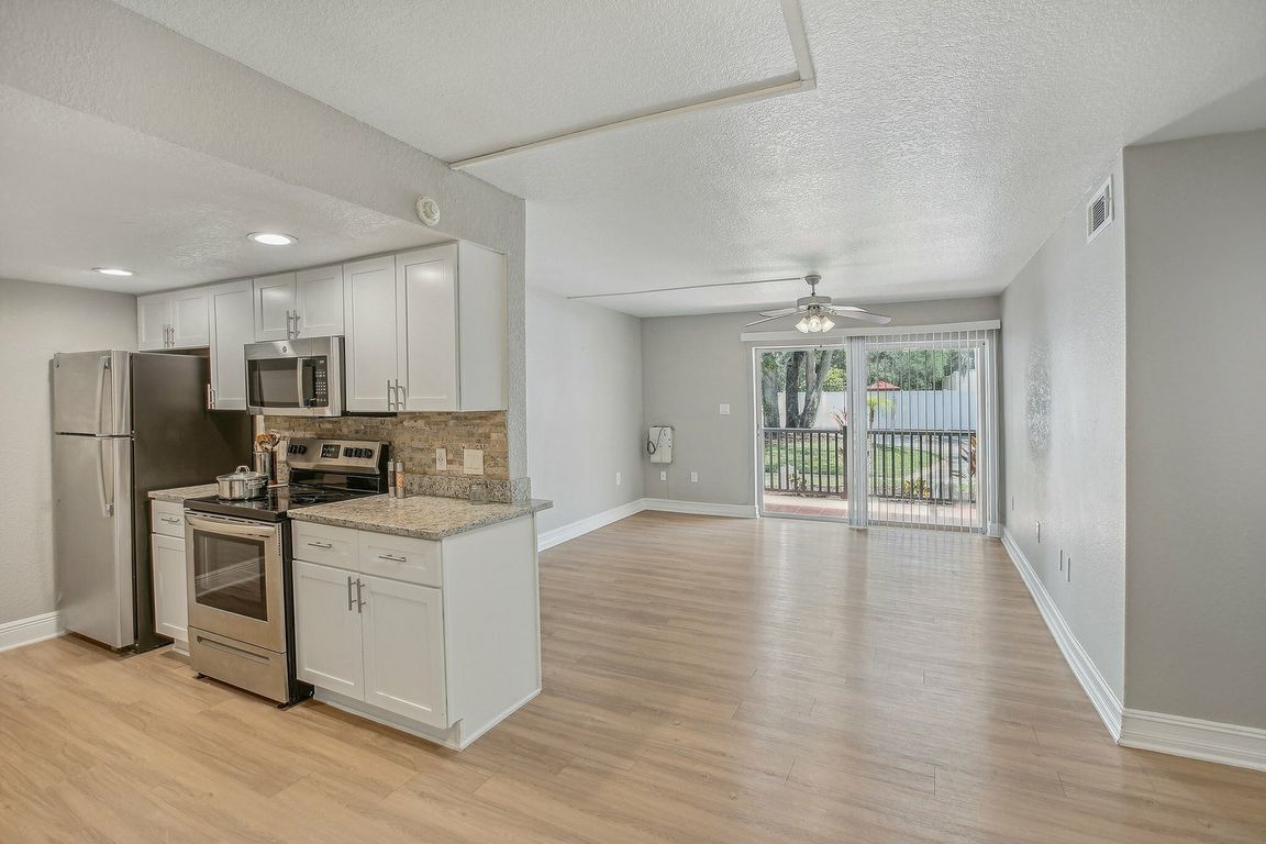 Bright open-concept kitchen and living area with sleek stainless steel appliances and large sliding glass doors leading to a beautiful outdoor view.