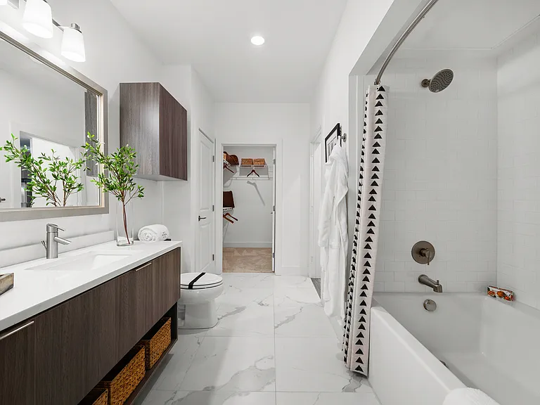 Spa inspired bathroom with dual vanity countertops, linen closet and large soaking tub