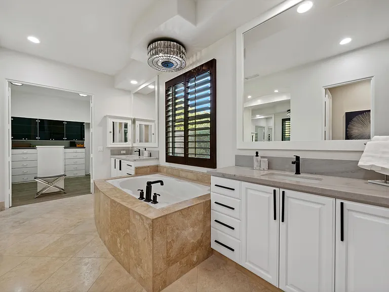 Primary bathroom with walk in shower, dual sink vanities, and additional vanity/glam station