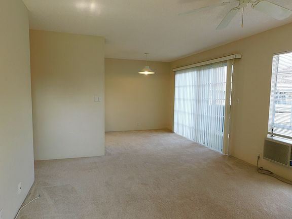 Front front door through living and dining area. Window a/c and ceiling fan. Covered lanai is on the right.
