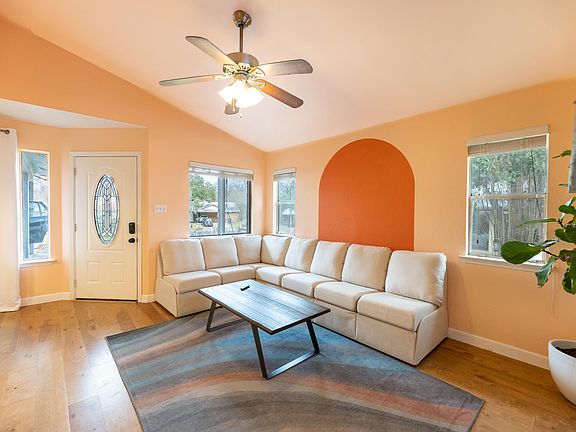 The living room has high vaulted ceilings, and a custom couch (available for purchase) with spacious seating for friends to enjoy time together in this colorful Austin home before heading to restaurants like Uchi, Loro, AGBG, Elizabeth St Cafe, and more.