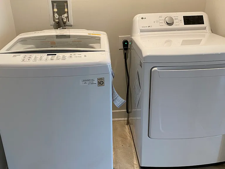 Laundry room with a big capacity washer and dryer and shelving units.